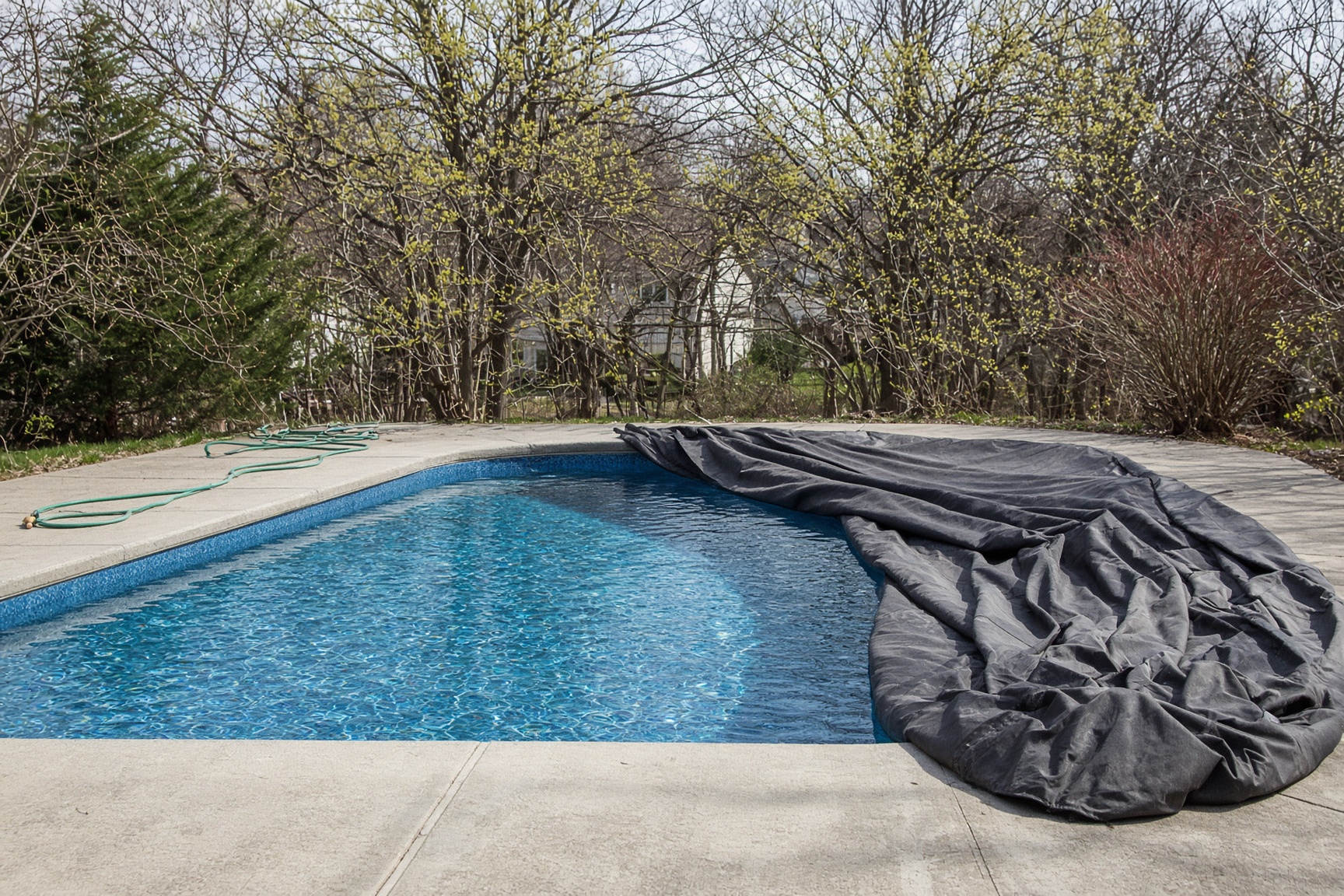 A winter cover pulled back from a residential swimming pool